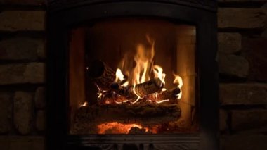 Ahşap odunlar ve alevler içinde yanan şömine. Sıcak ışık, kapalı mekanda romantik atmosfer