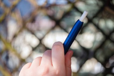 Elinde e-sigara tutan bir kadın. Elektronik sigara içmeyi kapat. Alternatif nikotin ısıtma ürünü