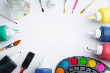 Ressam stüdyosundaki beyaz arka planda akrilik boya ve boya fırçalarının renkli paleti. Yaratıcılık ve eğitim kavramı. Hiç kimse, mesaj için boşluk