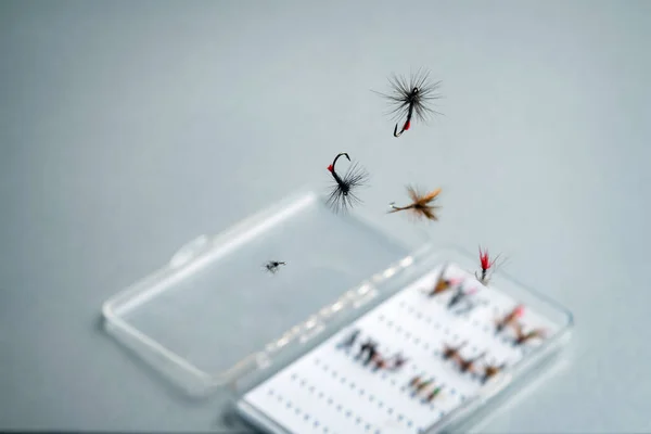 Close up of fly fishing flies levitating above the box with hooks. Fishing equipment still life. Nobody