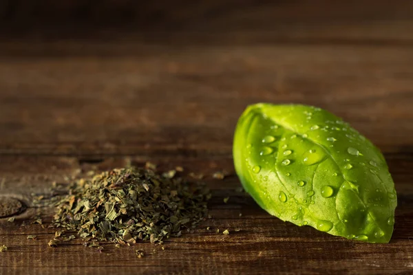 Basil leaves and dried basil on an old wooden table.