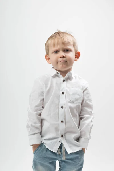 Portrait d'un garçon charismatique élégant et à la mode, fronçant les sourcils et sérieux dans une chemise blanche sur un fond blanc . — Photo