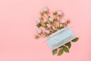 Tıbbi solunum koruyucu yüz maskesi ve pembe arka planda zarif güller, koronavirüs ve covid-19. Bahar kavramı, olumlu düşünceler ve romantizm hastalıktan sonra hayat devam eder..