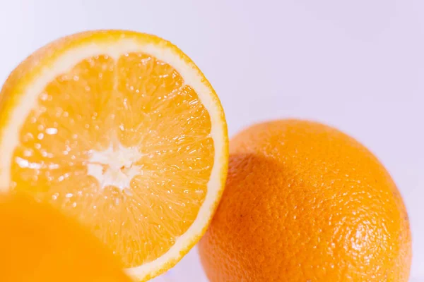 Naranja a la mitad cerca de una naranja completa sobre un fondo blanco — Foto de Stock