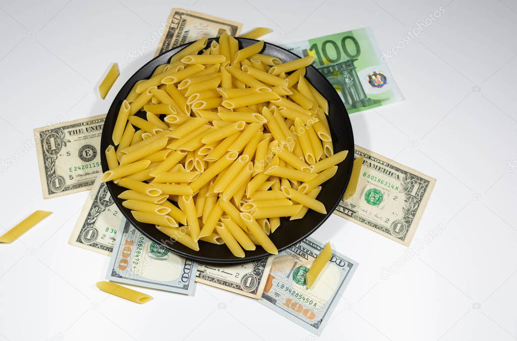 Pasta on a black plate under which lies money dollars