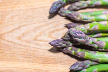 Kuşkonmaz, sağ taraftaki mutfak tahtasının üzerinde. Fotoğrafın notlar için ahşap bir arka planı var..
