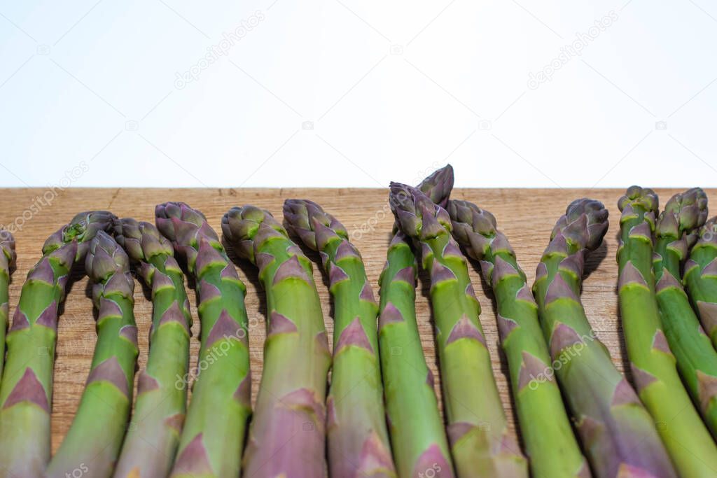 Asparagus evenly lying on the kitchen board. In the photo there is a place for recordings over asparagus.