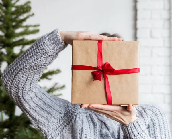 Ambachtelijk papier verpakt doos in hand met kerstboom — Stockfoto