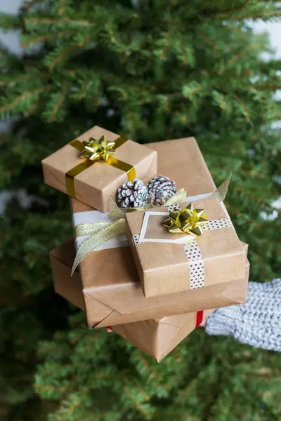 Present\'s boxes in hand with Christmas tree at background