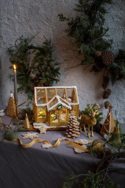 Arka planda Noel ağacı çelenkleri olan perili zencefilli kurabiye evi. Tatil dekorasyonu