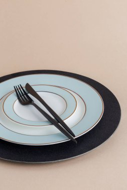 Bej arka planda çatal ve bıçakla servis tabağı boş. Siyah çatal bıçaklı servis tabağı.