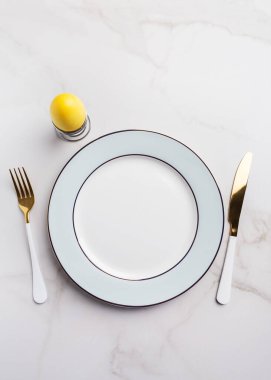 Sarı yumurta, altın ve beyaz bıçak ve beyaz arka plan çatallı Paskalya masası. Tatil yemeği seti kavramı