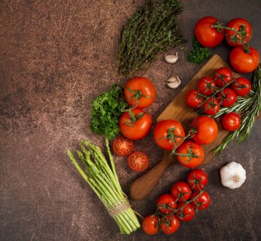 Kırmızı domates, kekik, biberiye, sarımsak, maydanoz ve paslı kuşkonmaz. Üst manzara, düz yatış, yukarıdan manzara. Sağlıklı gıda malzemeleri kavramı
