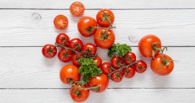 Beyaz ahşap arka planda yeşil maydanozlu taze kırmızı domatesleri kapatın. Sağlıklı İtalyan yemekleri için içerikli fotokopi alanı resmi kavramı