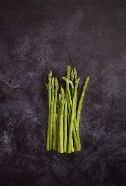 Koyu beton arka planda kuşkonmaz. Metin için sağlıklı yiyecek malzemeleriyle fotokopi alanı ile çerçevele. Üst görünüm, düz görünüm, yukarıdan görüntü