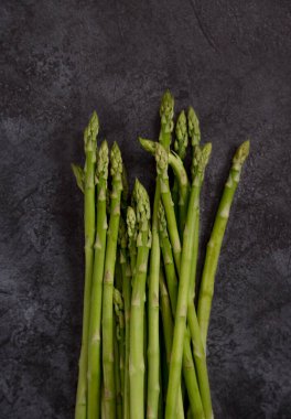 Koyu beton arka planda kuşkonmaz. Metin için sağlıklı yiyecek malzemeleriyle fotokopi alanı ile çerçevele. Üst görünüm, düz görünüm, yukarıdan görüntü