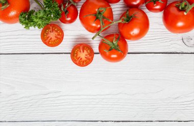 Beyaz ahşap arka planda yeşil maydanozlu taze kırmızı domatesleri kapatın. Sağlıklı İtalyan yemekleri için içerikli fotokopi alanı resmi kavramı