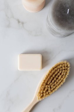 Vücut masajı için fırça, eller ve vücut için sabun ve mermer arka planda dekoratif mumlar. Kaplıca ve güzellik salonu için çok az yer var. Düz konum, yatay konsept, temizliğe hazır kadın konsepti