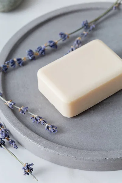 Close up aroma soap for hand with lavender flowers at stone dish on white marble background in bathroom. Concept of clean and beauty minimal set for female bathroom