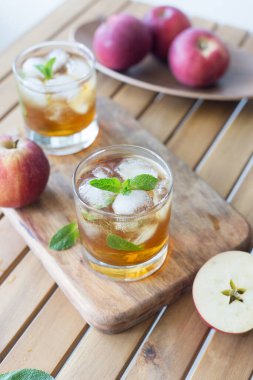 Nane ve buzlu taze elma suyu. Ahşap masanın yanında elmalarla tahta tahtada duran iki bardak. Yaz sıcağı için taze içecek kavramı