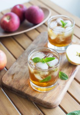 Kırsal tarzda ahşap arka planda buzlu ferahlatıcı elma suyu ile bardağı kapat