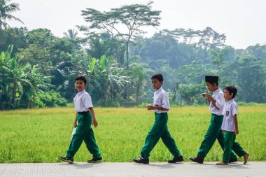 West Java, Indonesia - April 12, 2018: Indonesian schoolchildren walk along a rural road