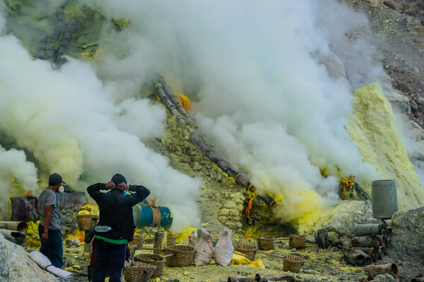 Ijen Volcano, Indonesia - April 1, 2018: Workers mine sulfur from the crater of the volcano