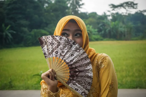 在稻田的背景上带着扇子的印度尼西亚女孩 — 图库照片