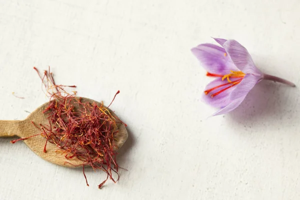 Tipos de açafrão em uma colher e flor de açafrão em um backgroun branco — Fotografia de Stock