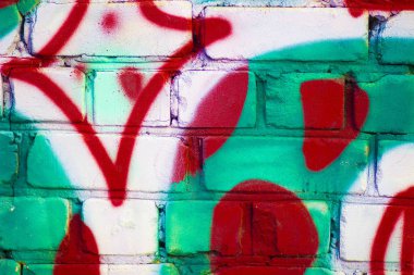 Caddedeki tuğla bir duvarda grafiti renkli desenler.