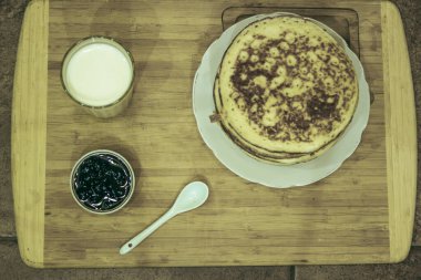 Maslenitsa bayramı için Rus gözlemesi, bir bardak süt ve yaban mersini reçeli.