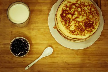 Maslenitsa bayramı için Rus gözlemesi, bir bardak süt ve yaban mersini reçeli.