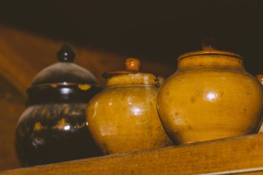 Rafta kapaklı bir sıra kil çömlek - köylü yemekleri