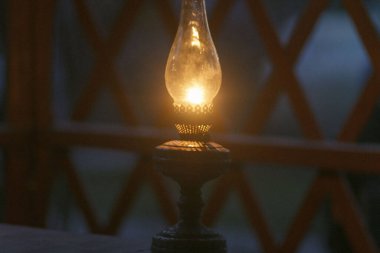 Eski, antika, eski bir gazyağı, cam gölgesi ve yanan bir ateşle retro bir lamba.