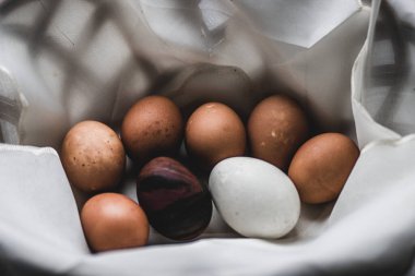 Hasır bir sepette beyaz havluya boyanmış Paskalya yumurtaları.