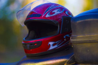 Spor motosikletinin deri koltuğunda bisiklet sürmek için kırmızı koruyucu kask.