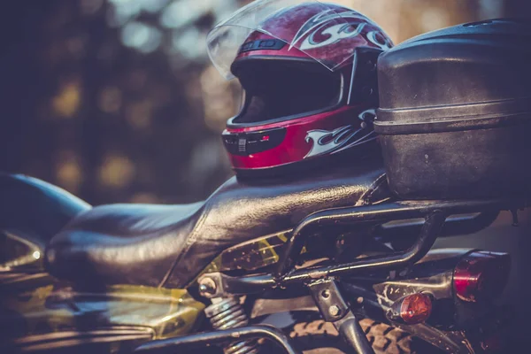 Spor motosikletinin deri koltuğunda bisiklet sürmek için kırmızı koruyucu kask.