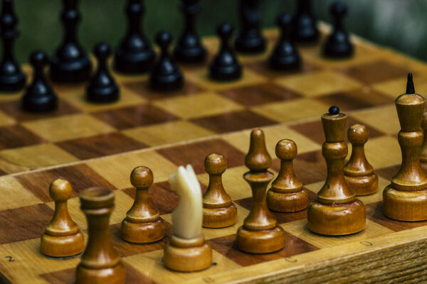 Black and white pieces on a wooden chess Board for playing chess