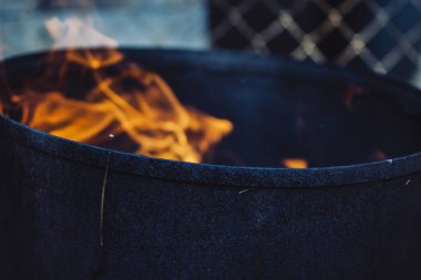 Eski paslı demir bir çöp varilinde kavurucu bir ateş.