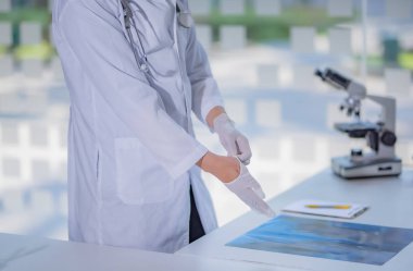 Beyaz tıbbi eldiven takan bir erkek doktorun resmi.