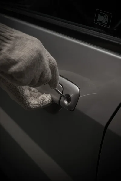 Car thief with glove trying to open a vehicle door by screw driver — Stock Photo, Image