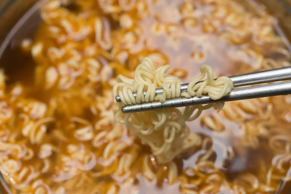 Chopstick picking up instant noodles with beef flavor sauce — Stock Photo, Image