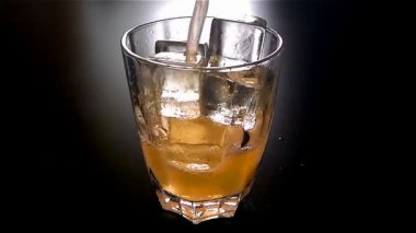 Karanlıkta 120 fps'de ağır çekimde bardak bira buz küpleri ile dökme