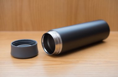 ahşap bir masa üzerinde siyah vakum tumbler