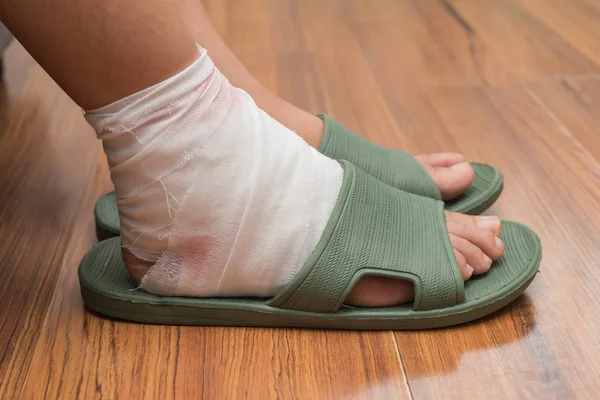 Lady with a wrapped foot on floor — Stock Photo, Image