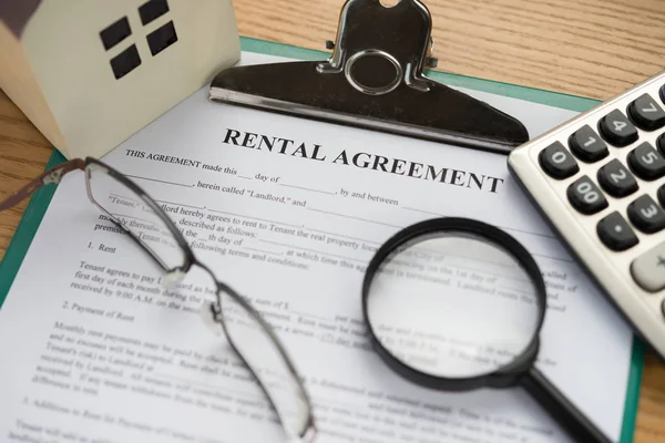 Rental agreement contact with an architectural model and a calculator and glasses and magnifier — Stock Photo, Image