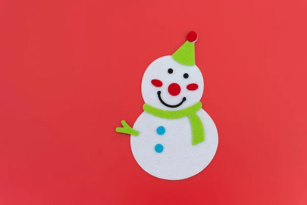 Flaches lächelndes Spielzeug Weihnachten Schneemann mit grünem Schal auf rot — Stockfoto