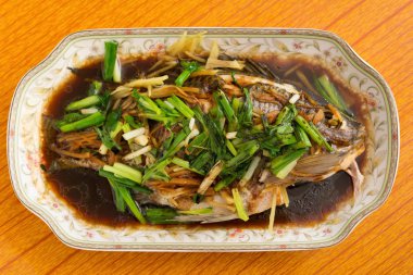 Bütün balık buğulama taze otlar soğan ve sos ile kaplı