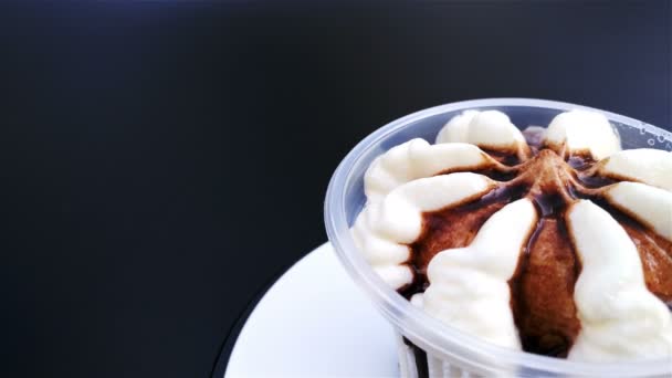 Xícara de sorvete de sabor de chocolate girando em fundo preto com espaço de cópia 4K — Vídeo de Stock