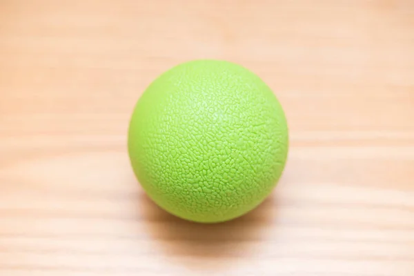 Petite boule de massage verte sur une table en bois — Photo